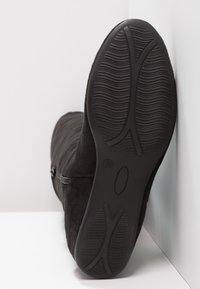 Botín de ante negro con superficie texturizada, cierre con cremallera y suela de goma flexible con un patrón de relieve para agarre. Talla 37.