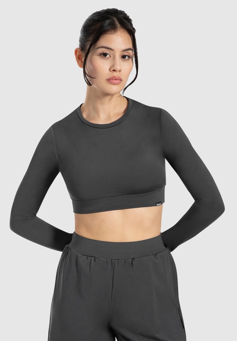 Top corto a maniche lunghe grigio scuro, in tessuto elasticizzato. Texture liscia, collo rotondo e design aderente, abbinato a pantaloni a vita alta.