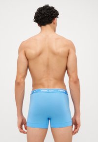 Modré bavlnené boxerky s bielym logom Nike na elastickom pásku, s hladkou textúrou a priliehavým dizajnom.