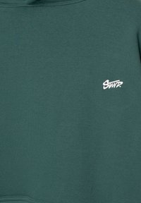 Grüne Sweatshirt aus weichem Baumwollmaterial, mit einem kleinen, weißen gestickten Logo auf der Brust. Glatte Textur, Rundhalsausschnitt.
