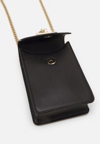 Musta, teksturoitu nahkainen olkalaukku, jossa on kultaketjuhihna ja napsautuslukitus, esiteltynä avoimena valkoista taustaa vasten.