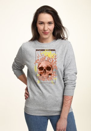 Šedá mikina s velkým potiskem lebky v oranžové barvě, obklopená textem ve stylu graffiti v různých barvách. Ribovaná manžeta a lem.