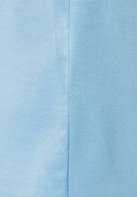 Helles blaues Fabrik mit glatter Textur; auf der linken Seite befindet sich eine Naht mit dezentem, vertikal verlaufendem Rippendetail.