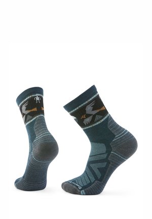 Knöchellange Socken in Dunkelblau und Grau, mit einem geometrischen Muster und einem Akzentband mit Vögeln. Hergestellt aus einem weichen, elastischen Material.