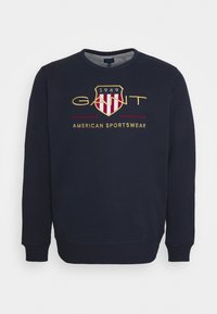 Felpa blu marina in cotone misto, con scollatura rotonda, maniche lunghe e logo ricamato in rosso e oro con un design a scudo.