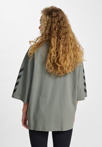 Oversized groene shirt met korte mouwen, voorzien van zwarte diagonale strepen op de mouwen en een gladde, lichte stof.