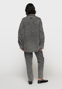 Set di giacca in denim oversize e pantaloni grigi con un motivo sottile. Presenta grandi tasche e maniche a polsino. Include mocassini neri.