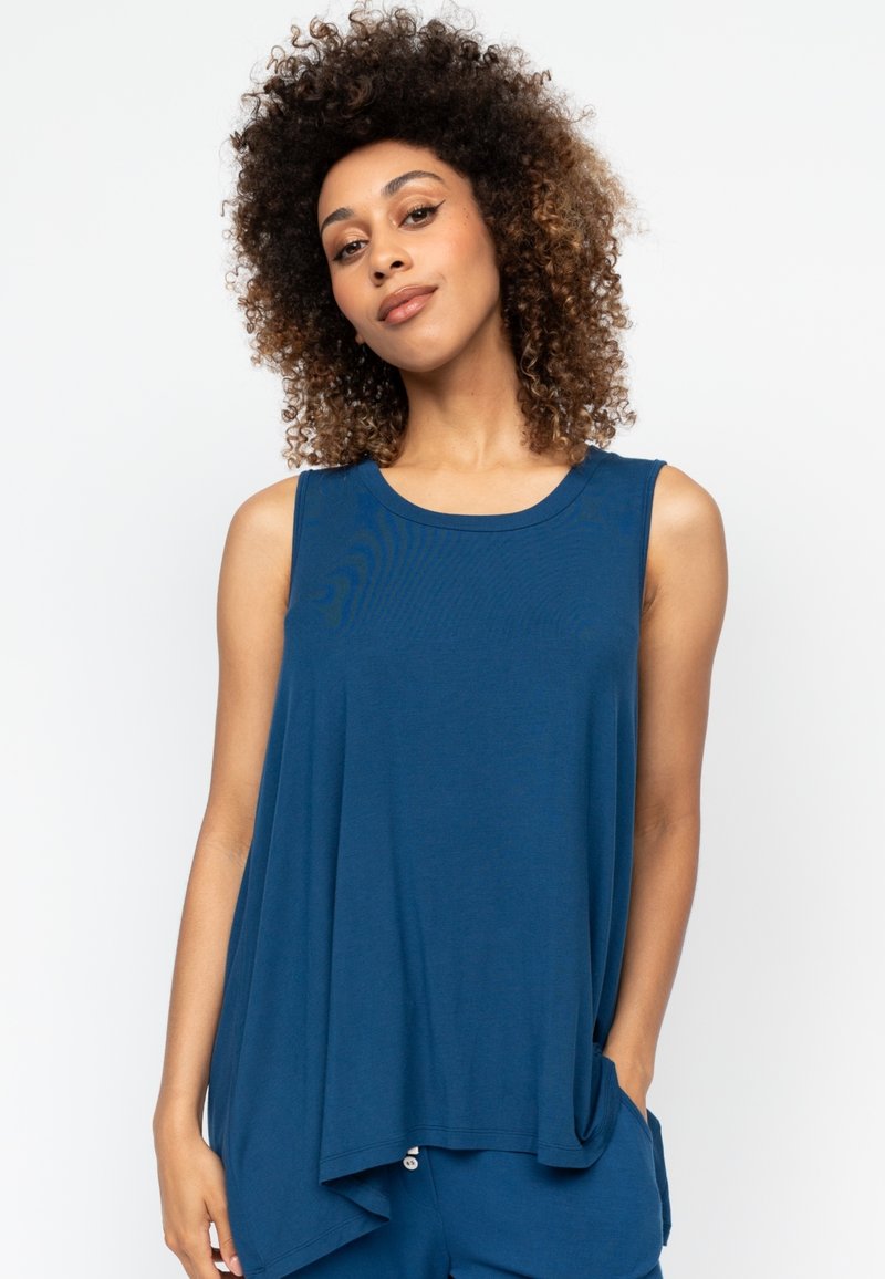 Mouwloos blauw topje van zacht materiaal, met een losse pasvorm, afgeronde halslijn en zijzakken voor gemak.