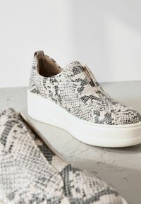 Baskets slip-on avec un motif en peau de serpent noir et gris, dotées d'une semelle compensée et d'un dessus texturé. Semelle extérieure en caoutchouc blanc.
