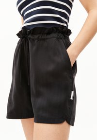 Black shorts made of lightweight fabric with an elastic waistband, ruffled top, drawstring, and side pockets. Tag on the side seam.
