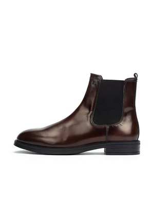 Botas Chelsea de cuero marrón con paneles elásticos en los laterales y una pestaña en el tobillo. Textura suave, puntera redondeada y suela de goma.