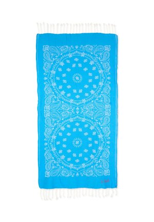 Felblauwe rechthoekige sjaal met witte paisley- en cirkelpatronen, franjes aan de randen en een kleine rode handtekening in de hoek.