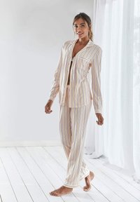 Striped pajama set in pastel colors with a button-up shirt, chest pocket, and drawstring pants. Soft fabric, relaxed fit, long sleeves.