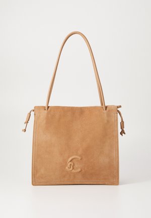 Sac fourre-tout en daim couleur tabac, avec de longues poignées, des détails à cordon de serrage sur les côtés, et un logo abstrait subtilement embossé au centre devant.