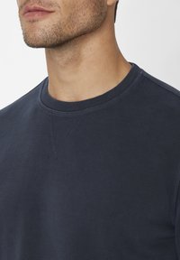 Marineblaues Strick-Sweatshirt mit Rundhalsausschnitt und gerippten Bündchen, aus strukturiertem Stoff mit sichtbaren Nähten am Ausschnitt.