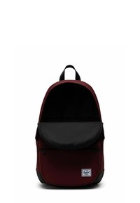 Sac à dos rouge et noir de forme arrondie, en tissu, avec rabat frontal, ouverture par le haut, et patch logo sur le bas devant.