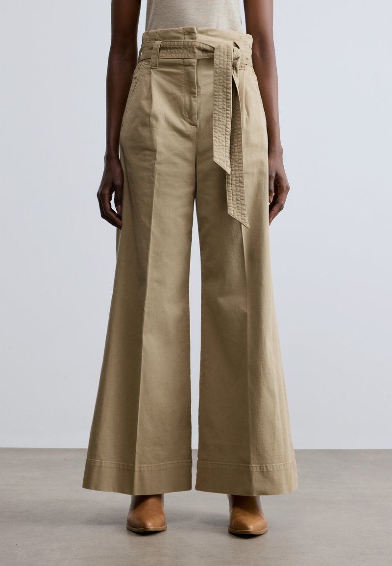 Pantaloni bej cu picior larg și talie înaltă, având o curea texturată, buzunare laterale și un material neted din bumbac.