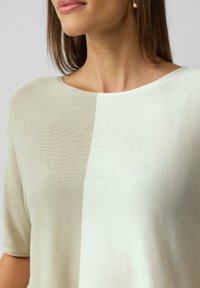 Lekki sweter dzianinowy w odcieniach beżu i kremu, z okrągłym dekoltem, krótkimi rękawami i gładką fakturą z subtelnym blokowaniem kolorów.