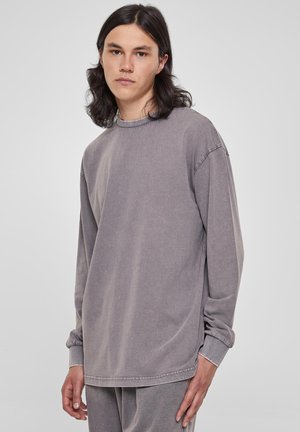 Sweatshirt à manches longues et col rond en mélange de coton gris délavé. Présente une coupe ample, des détails cousus et des poignets côtelés. Texture lisse sur l'ensemble.