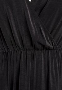 Primer plano de un vestido de tela de carbón oscuro con cintura fruncida y detalle de escote en V en forma de envoltura.