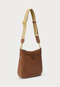 Bolsa de ombro em pele castanha com um acabamento texturado, ferragens douradas e um detalhe com o logótipo. A alça ajustável apresenta um padrão do logótipo.