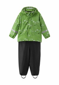 Zielona kurtka przeciwdeszczowa z białym wzorem kwiatowym i odblaskowymi paskami, połączona z czarnymi spodniami wodoodpornymi z elastycznymi mankietami i regulowanymi paskami.