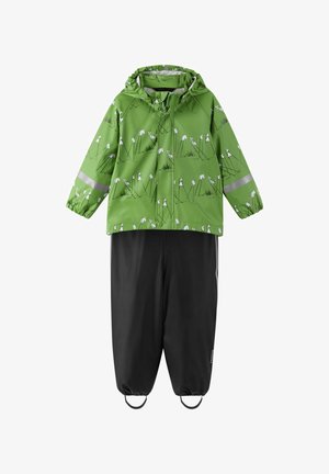 Zielona kurtka przeciwdeszczowa z białym wzorem kwiatowym i odblaskowymi paskami, połączona z czarnymi spodniami wodoodpornymi z elastycznymi mankietami i regulowanymi paskami.