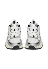 Fehér és ezüst fűzős sportcipők, hálós felsőrész, párnázott bokarész, texturált kiegészítők és fekete gumi talp jellemzi.