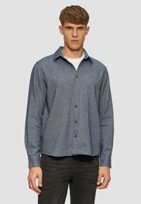 Blauw button-up shirt van textuurstof, met een spitse kraag, lange mouwen en een gebogen zoom, gecombineerd met donkere jeans.