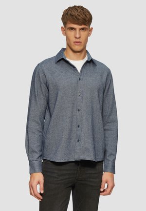 Blauw button-up shirt van textuurstof, met een spitse kraag, lange mouwen en een gebogen zoom, gecombineerd met donkere jeans.