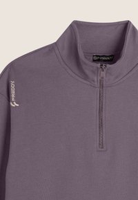 Felpa viola con zip e colletto alto, caratterizzata da un logo discreto sulla spalla sinistra e un tessuto testurizzato. Dettaglio della zip in evidenza.