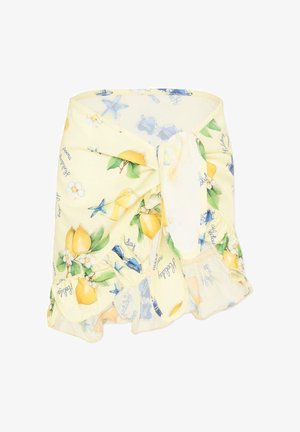 Żółta spódnica na zakładkę z motywami cytryn, białych kwiatów i niebieskich rozgwiazd, zawiązana na supeł i z falbanką na dole.