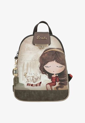 Mochila pequeña beige y marrón con una niña de dibujos animados con vestido rojo, texto "Yourself" y detalles decorativos de metal y tela.