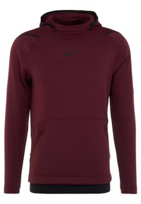 Bordeaux Nike hoodie med høj hals, sorte accenter og en frontlomme. Lavet af glat stof, med en tætsiddende design og lange ærmer.