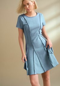 Vestido corto de manga corta en azul claro, hecho de tela texturizada, con un cuello redondo y un diseño con pliegues que incluye bolsillos a los lados.