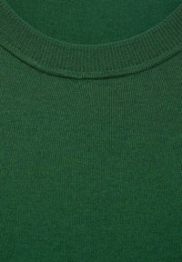 Gros plan sur un tissu tricoté côtelé vert foncé avec un col rond sur un vêtement.