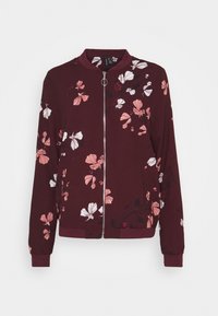 Giacca bomber color bordeaux con motivo floreale in rosa e bianco. Realizzata in tessuto morbido con chiusura a zip e polsini a costine.