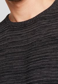 Maglioncino grigio scuro con texture, dotato di un colletto a girocollo a costine, caratterizzato da un leggero motivo a righe orizzontali e un materiale morbido a maglia.