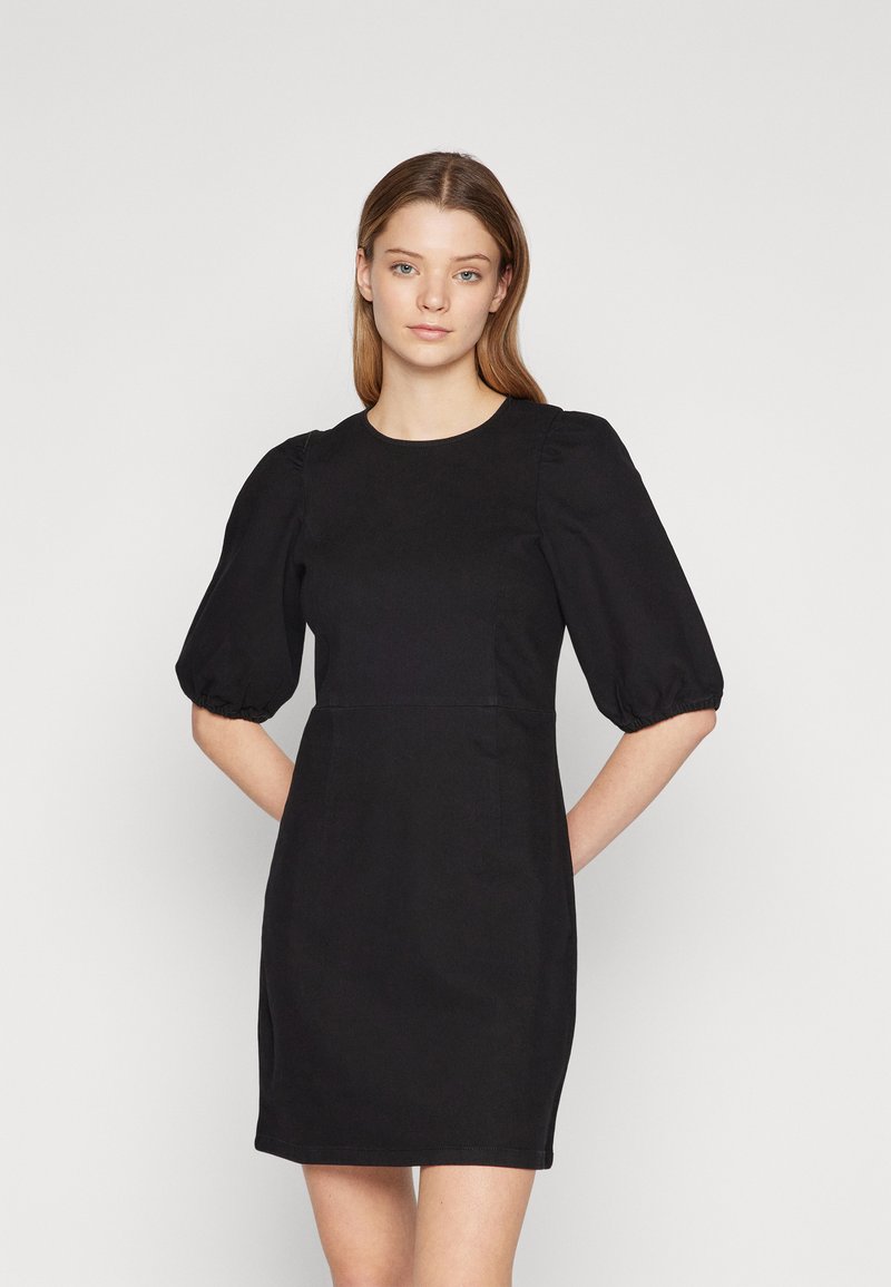 Robe noire avec des manches bouffantes courtes, un col rond et une silhouette ajustée. Fabriquée dans un tissu lisse avec des détails de couture minimalistes.