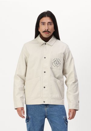 Beige, lichtgewicht jack met knoopsluiting, twee voorkruiszakken en een logo patch op de linkerkant van de borst. Kenmerkt zich door een klassiek kraag en lange mouwen.