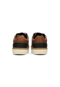 Bruine en zwarte leren schoenen met een ronde neus, zandkleurige stiksels en een witte rubberen zool, voorzien van een getextureerd achterpaneel.
