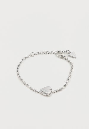 Silver chain bracelet featuring a heart-shaped charm with a crystal accent and engraved detail. Simple clasp with triangle tag attached.