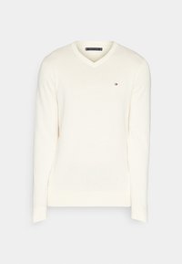 Maglione v-neck color crema con maniche lunghe, realizzato in un morbido tessuto a maglia. Presenta un piccolo logo ricamato in rosso, bianco e blu.