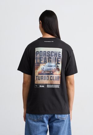 T-shirt in cotone nero con grafica vintage di una Porsche sul retro, caratterizzata da testo audace e un aspetto testurizzato. Vestibilità ampia, maniche corte.