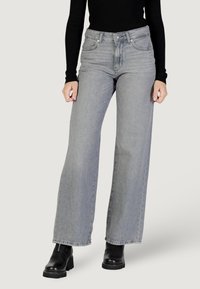 Jeans in denim grigio a gamba larga con finitura sbiadita, vita alta e design classico a cinque tasche, abbinati a stivaletti neri alla caviglia.