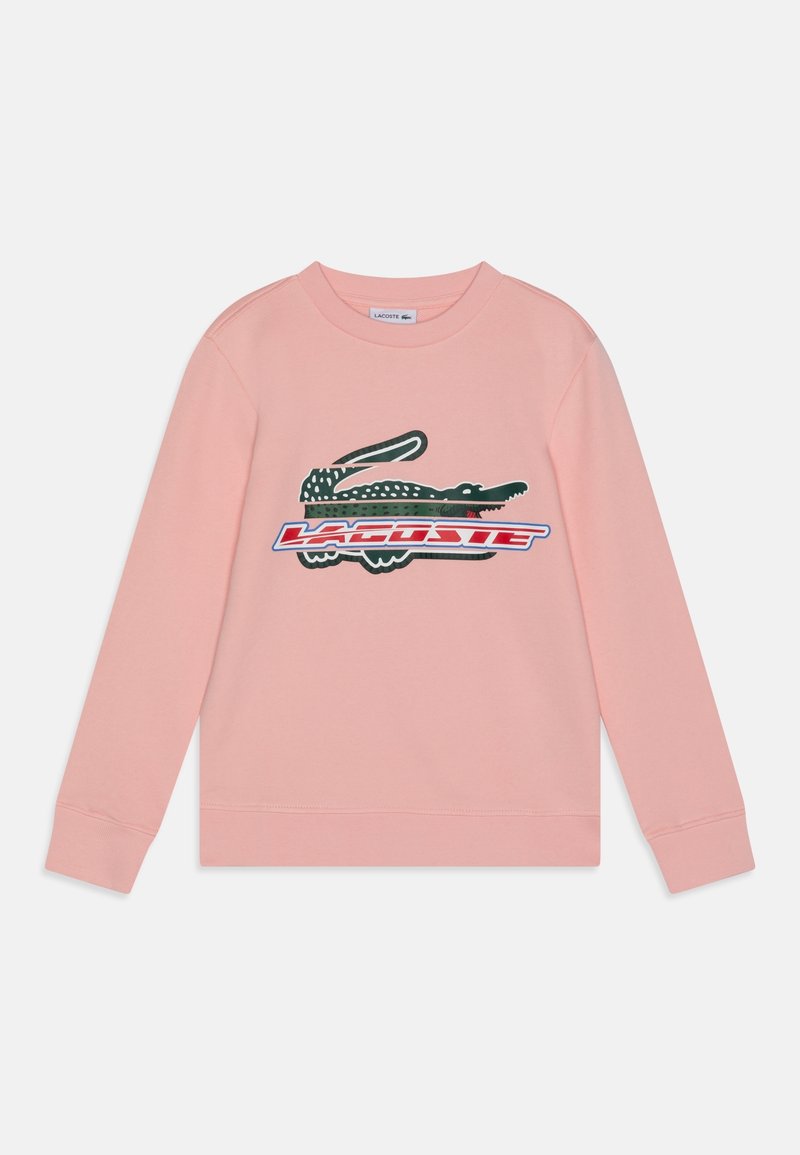 Sweatshirt en coton rose avec des manches longues, un col côtelé, et un grand graphique d'un crocodile avec le mot "LACOSTE" en rouge et bleu.