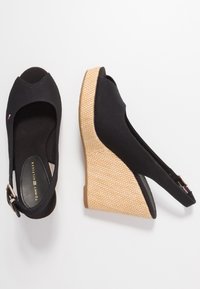 Sandali a zeppa neri con tomaia in tessuto, design open-toe e texture intrecciata simile al giunco sul tacco a zeppa. Dettaglio con fibbia sul lato.