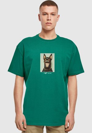 Grøn bomulds T-shirt med et stort grafisk motiv af en gøende hund i midten, med en sort krave og et afslappet fit design.