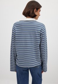 Camicia a maniche lunghe a righe blu navy e azzurro con colletto bianco, realizzata in tessuto morbido, caratterizzata da un fitting rilassato e un orlo dritto.