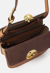 Borsa a mano in pelle marrone con chiusura in oro, dotata di una patta frontale in suede e diversi scomparti interni per l'organizzazione.